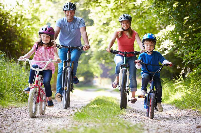 Family of four riding bikes on gravel road - iStock -462382789