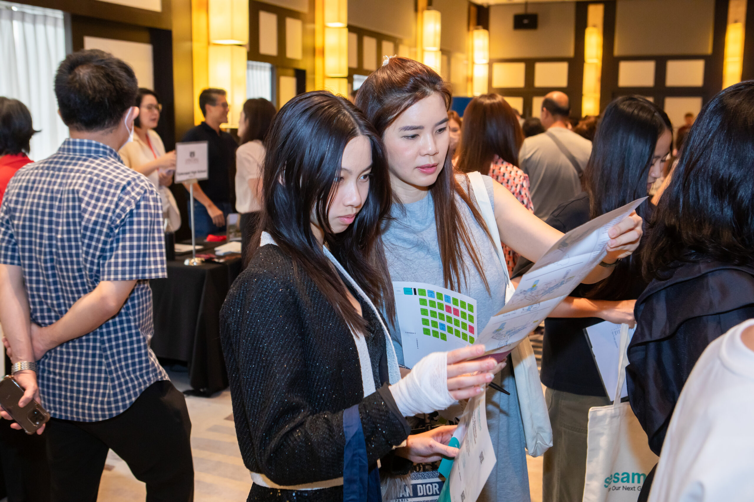 two girls looking at a brochure during a school fair