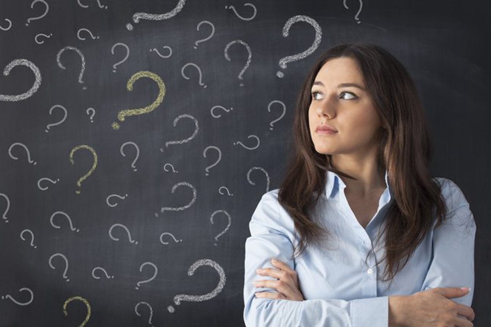 Woman looking confused at a blackboard of questions