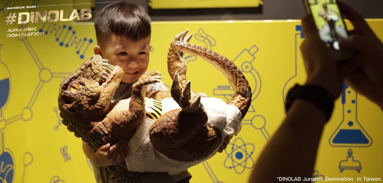 Boy carriyng a baby dinosaur as a Dino saurexhibition